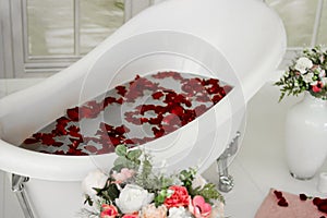 White bath with rose petals. Taking a bath with roses.