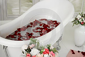 White bath with rose petals. Taking a bath with roses. photo
