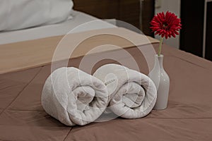 White bath towels roll on a bed in the hotel suite