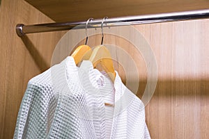 White bathrobes hanging in wardrobe