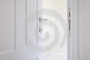 White bathroom door left ajar, slightly open doorway with modern handle