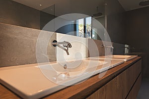 White bathroom sink in a new construction house with gray stone wall and wooden furniture