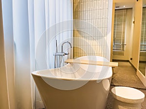 White bathtub with warm lighting against with hot and cold water faucet