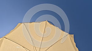 White beach umbrella. Blue sky in the background. View from below. Summer holidays by the sea. General contest and location