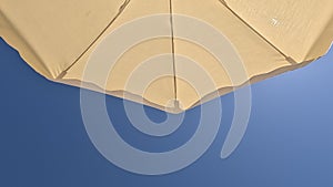 White beach umbrella. Blue sky in the background. View from below. Summer holidays by the sea. General contest and location