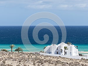 A white beach villa at turquoise ocean.