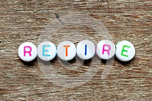 White bead with letter in word retire on wood background