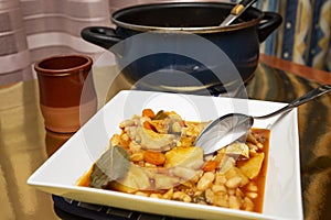 white bean and cod stew in a casserole and served on a plate with a spoon