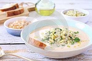White bean vegetarian cream soup with fried pearl barley and parsley, bread and olive oil
