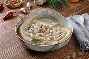 white beans soup with bread on kitchen table background