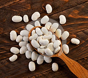 White beans in a spoon on a wooden background. The view from top