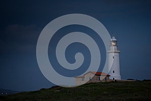 White beautiful lighthouse on the background of the night blue sky.