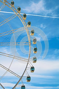 White beautiful modern ferris wheel with blue sky at the background.