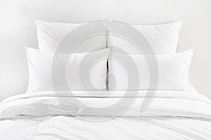 White bed , four white pillows and duvet on a bed