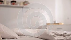 White bed with pillow and clean fresh bedsheets in light hotel room, HoReCa