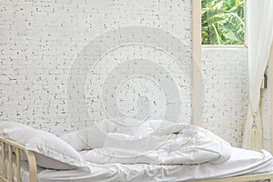 White bedding sheets and pillow in white room background. Messy bed concept in moring time