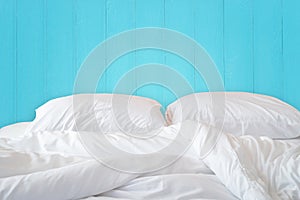 White bedding sheets and pillow on wooden wall room background,