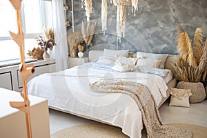 White bedroom interior with dry flowers, trendy loft design and white linens on double bed