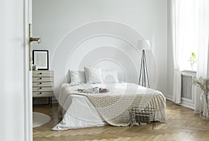 White bedroom interior in real photo with king-size bed with kni