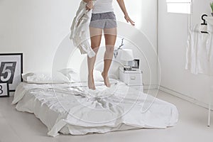 The white bedroom. Woman with a blanket jumping on a bed.