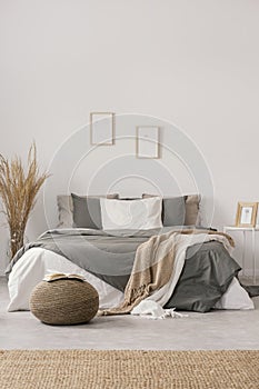 White and beige blankets on grey duvet on comfortable bed in bright bedroom interior photo