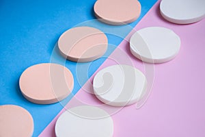 White and beige makeup cosmetic foundation sponges on the blue and pink background, Close up