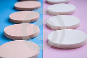 White and beige makeup cosmetic foundation sponges on the blue and pink background, Close up