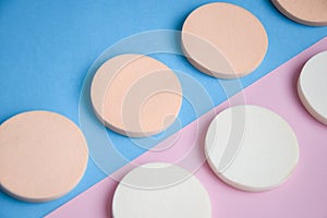 White and beige makeup cosmetic foundation sponges on the blue and pink background, Close up