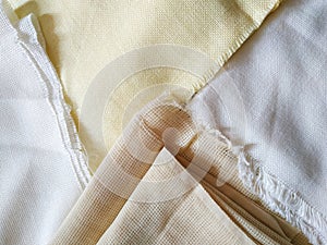 White, beige and yellow canvas with fringe close up. Fabric texture background
