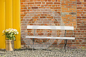 White bench in front of a brick wall