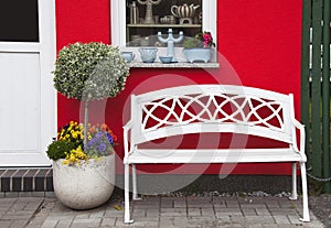 White bench in front of red house