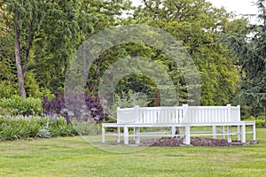 White bench in landscaped, mature english garden