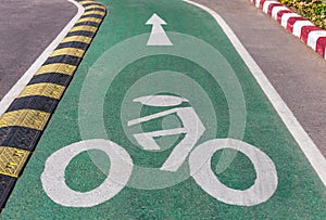 white bicycle lane sign on green asphalt road