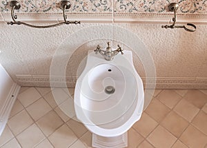 white bidet with a bronze faucet