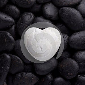 White big heart pebble, stone, rock laid on pile of black nature pebbles, stones, rocks with text space. 