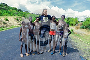 White Big Men Tourist posing near Benna Tribe Young Boys with Traditional Body Painting