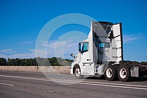 White big rig day cab semi truck with spoilers run on wide inter