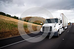 White big rig semi truck with dry van semi trailer driving in st