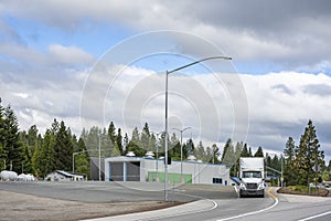 White big rig semi truck with loaded semi trailer leaves the weighing station complex after weighing on scales