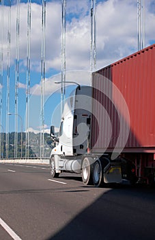 White big rig semi truck with long container driving on the arch