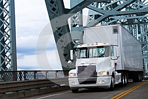 White Big rig semi truck and reefer on farm bridge