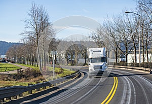 White big rig semi truck with semi trailer moving on turning local road