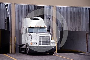 White big rig semi truck in warehouse dock