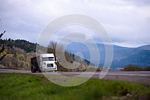 White big rig tipper running on gorgeous road with meadows mount