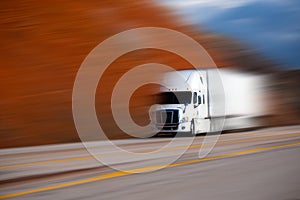 White big semi truck on the road on blurred colors background