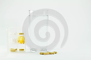 White bill box with pills, glass of water and pills on floor on