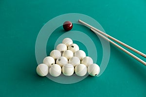 White billiard balls for Russian billiards, in a triangle and cue sticks on the table.