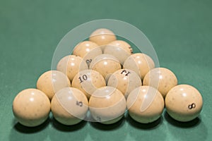 White billiard balls for Russian billiards, in a triangle on the table. Russian billiards balls and cue on the table, the pyramid