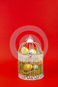 White bird cage with Easter eggs in it on a red background