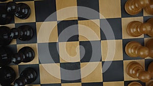 White and black chess pieces standing in row on wooden board